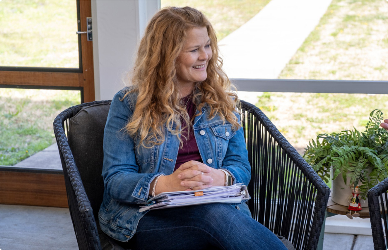 A smiling woman sitting with a binder in her lap