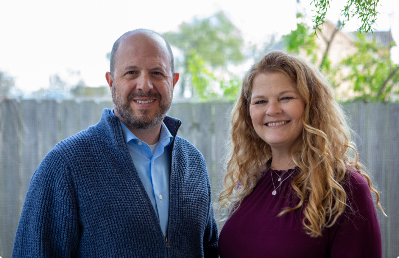 A man and woman standing in a back yard