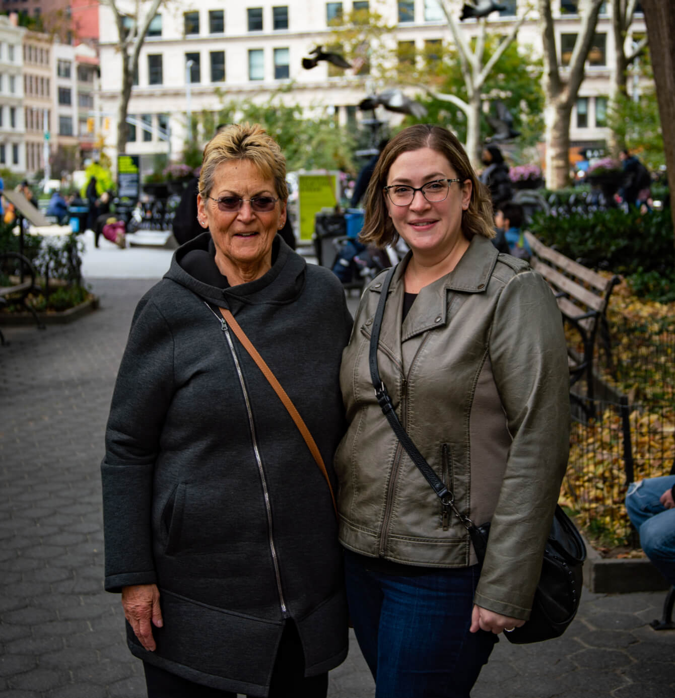 A female myelofibrosis patient and her female caregiver embracing and smiling for a photo in a park.