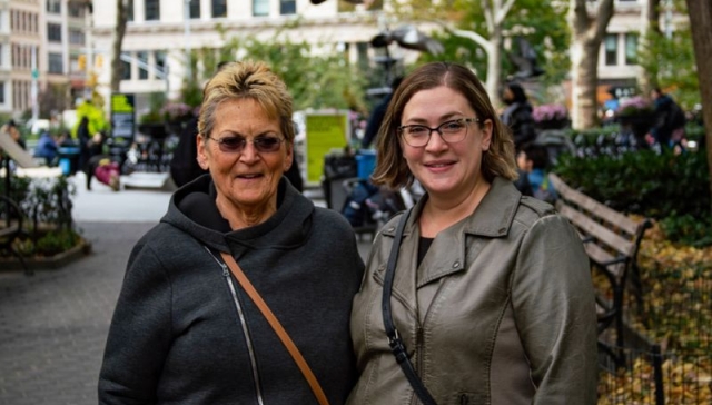 A female myelofibrosis patient and her female caregiver embracing and smiling for a photo in a park.